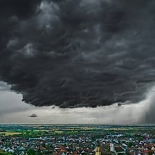Rain falling from dark clouds over a city