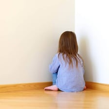 A child sitting in a time-out spot after misbehaving.