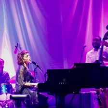 Norah Jones performing with a microphone and piano.