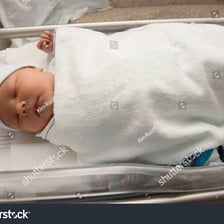 A newborn baby boy resting in a hospital bassinet