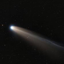 A bright comet with a visible tail crossing a dark night sky.
