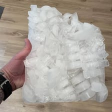 An ice cube melting on a surface after being taken from a freezer.