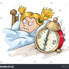 A person rising from bed beside a ringing alarm clock.