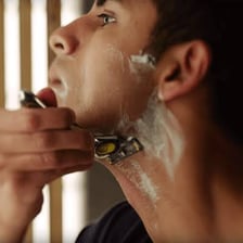 A person shaving their face with a razor