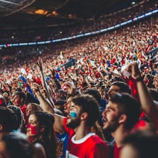 A crowd of enthusiastic fans cheering loudly in a stadium.