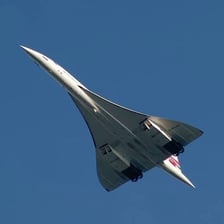 A Concorde supersonic transport aircraft flying above the ground