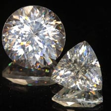 A faceted gemstone displayed with light reflecting from its surfaces.