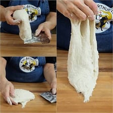 Hands pressing and folding bread dough