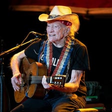 Willie Nelson performing with his guitar.