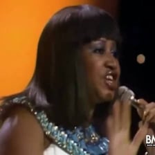 Aretha Franklin performing onstage with a microphone.