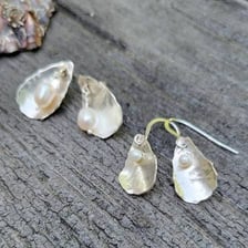 A cultured pearl shown with an oyster and jewelry.