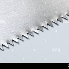 A close-up showing the pointed teeth along a hand saw’s blade.