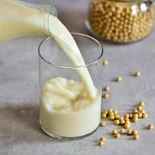Glass of soy milk beside soybeans.