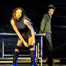 A stage scene depicting Mimi and Roger performing in Rent