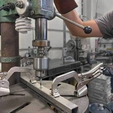 A power drill and a metal clamp in a workshop