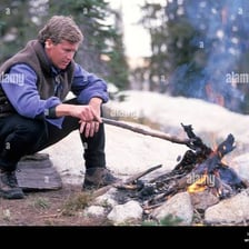 A person stirring and intensifying a fire.