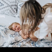A parent playfully tickling a laughing baby.