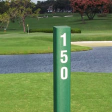 A yardage marker beside a golf-course fairway.