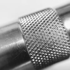 A close-up of a ridged knurled metal surface