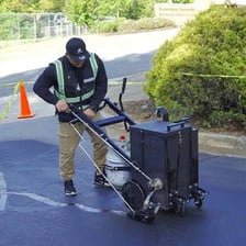 A road crew spreading dark sealant over pavement.