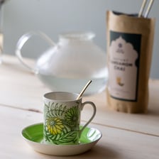 A cup of spiced chai with cardamom pods nearby.