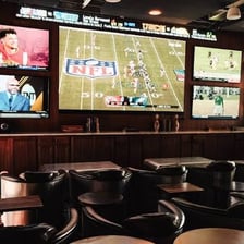 Several televisions showing sports in a bar.
