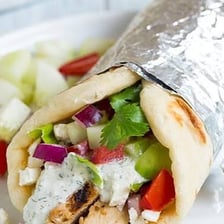 A Greek gyro wrap filled with meat, vegetables, and sauce.