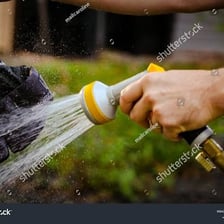 A person washing an object with a garden hose
