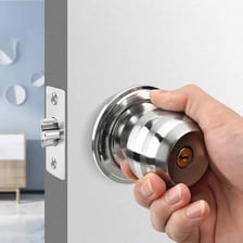 A hand turning a round door knob.