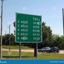 A highway toll sign showing charges based on vehicle axles