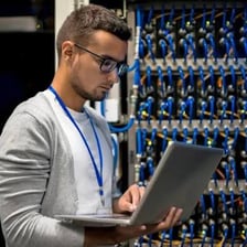 An information-technology support worker assisting someone at a computer.
