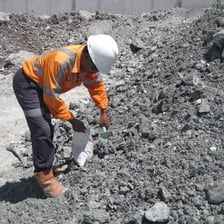 A miner inspecting a rock containing ore.