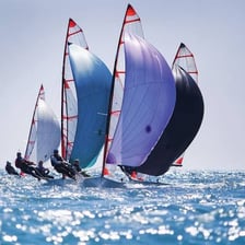 A sailboat moving across water with its sails filled by wind.