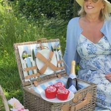 People placing sandwiches and other food into a picnic hamper.
