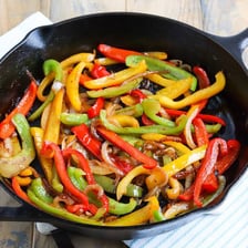 A sizzling fajita served in a hot skillet with peppers and onions.