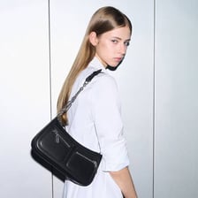 A person wearing a crossbody bag positioned at their side.
