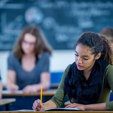 Students seated in a classroom taking a standardized test.