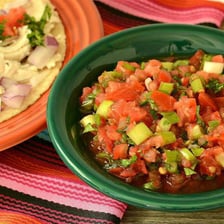 A sliced onion beside a bowl of salsa