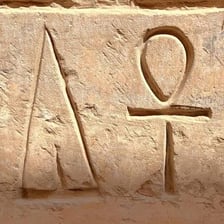 Ankh symbols carved into an ancient Egyptian stone surface.