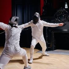 Two opponents facing each other in a fencing duel.