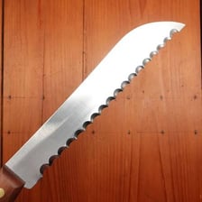 A close-up of a knife with a saw-edged serrated blade