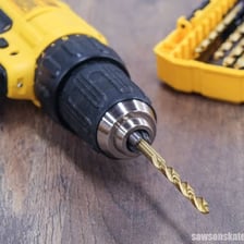 A metal drill bit attached to the chuck of a power drill