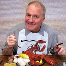 A diner wearing a bib while eating lobster