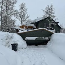 A house partially buried by snow, suggesting that its occupants are snowed in.