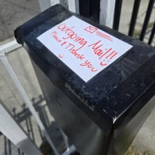 A hand placing a mailed letter into a mailbox.