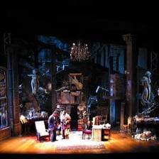 Actors performing a scene on a theater stage.