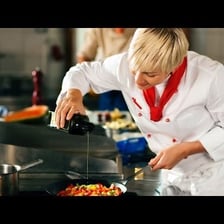 A sous-chef preparing food in a busy professional kitchen