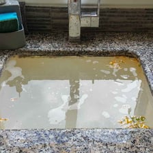 A household sink drain blocked by accumulated debris.