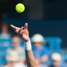 A tennis ball crossing near the net during a serve.