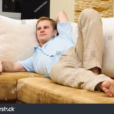 A person relaxing idly on a couch while watching television.